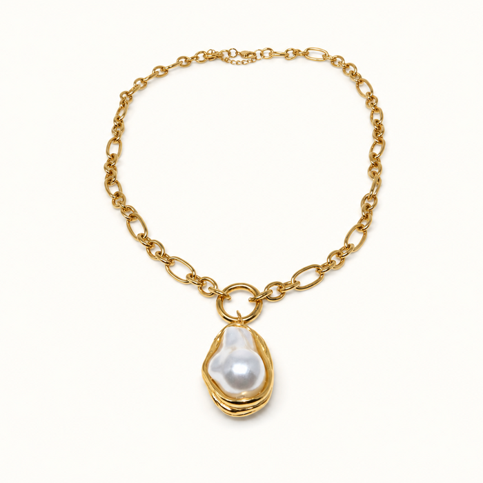 A gold chain necklace featuring a large, irregular white baroque pearl pendant set in a gold bezel, displayed on a clean white background.
