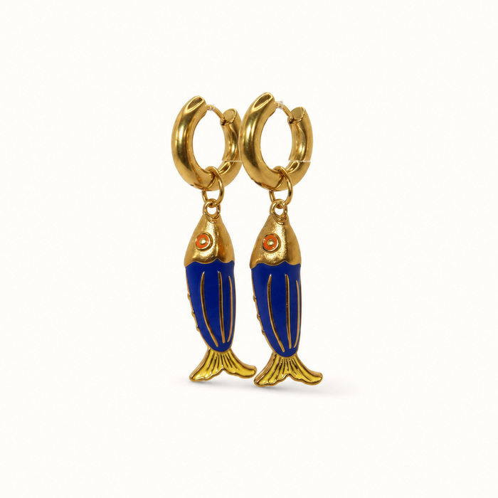 A pair of gold hoop earrings with dangling fish charms featuring deep blue enamel bodies and gold details, set against a plain white background.