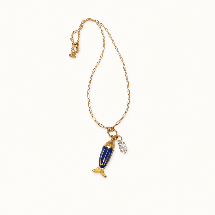 A delicate gold chain necklace featuring a stylized blue and gold fish charm, a small white pearl-like bead, and a tiny gold charm, displayed on a clean off-white background.