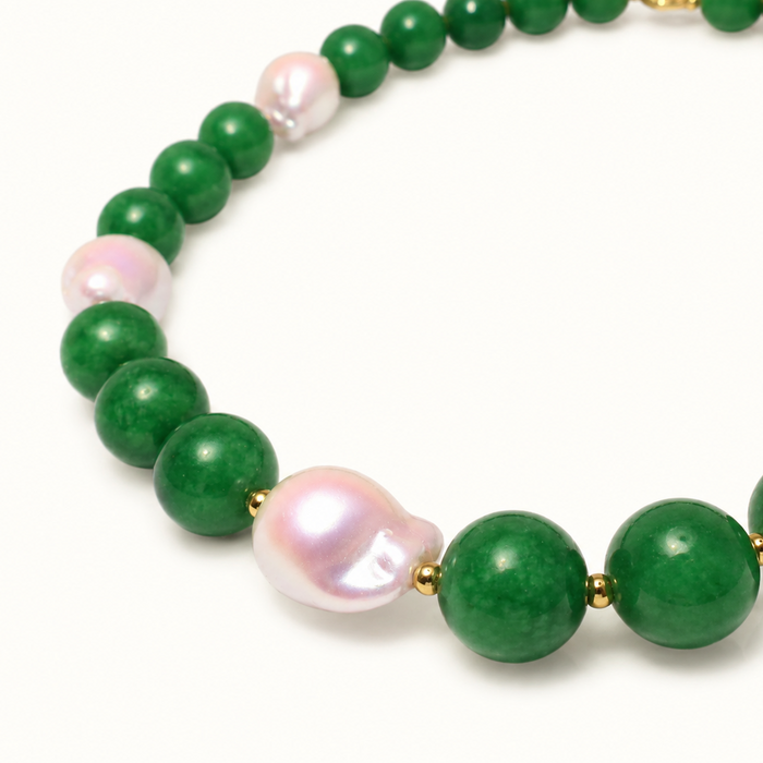 A beaded necklace featuring round green jade-like beads and irregular, lustrous pink freshwater pearls separated by small gold spacer beads, shown on a clean white background.