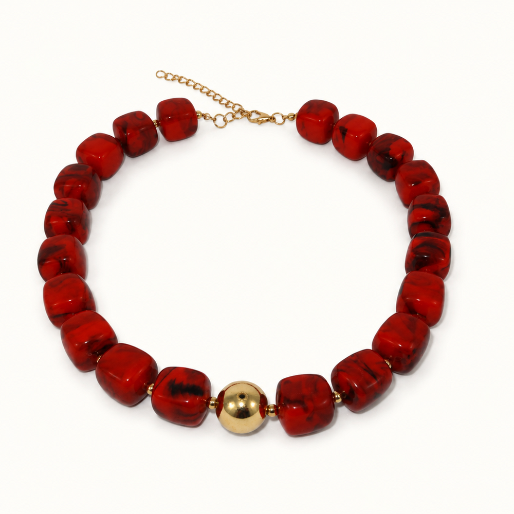 A red beaded necklace with chunky, rounded square beads and a central gold ball accent, displayed on a clean white background.