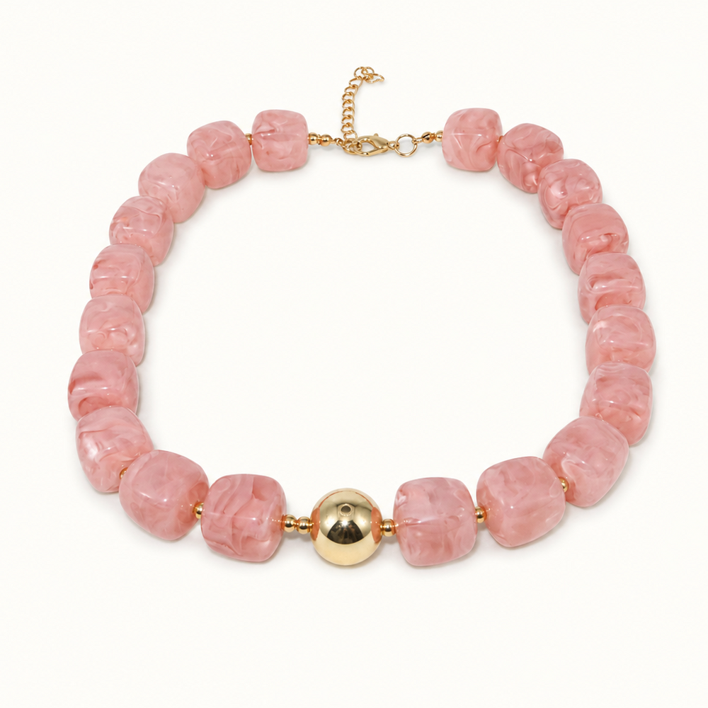 A pink stone bead necklace with a central gold ball accent and gold-toned clasp, shown on a plain white background.