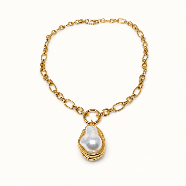 A gold chain necklace featuring a large, irregular white baroque pearl pendant set in a gold bezel, displayed on a clean white background.