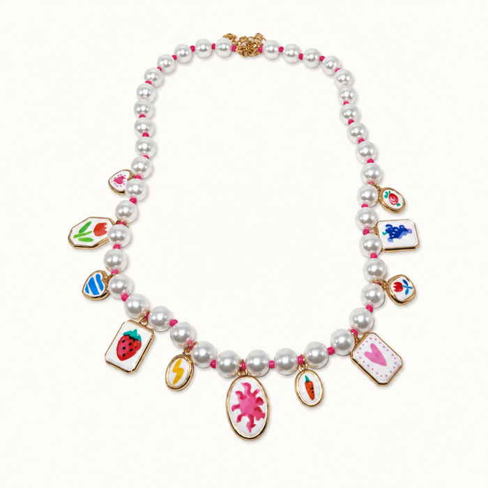 A pearl necklace with gold-tone hardware and multiple colorful enamel charms, displayed on a clean off-white background.