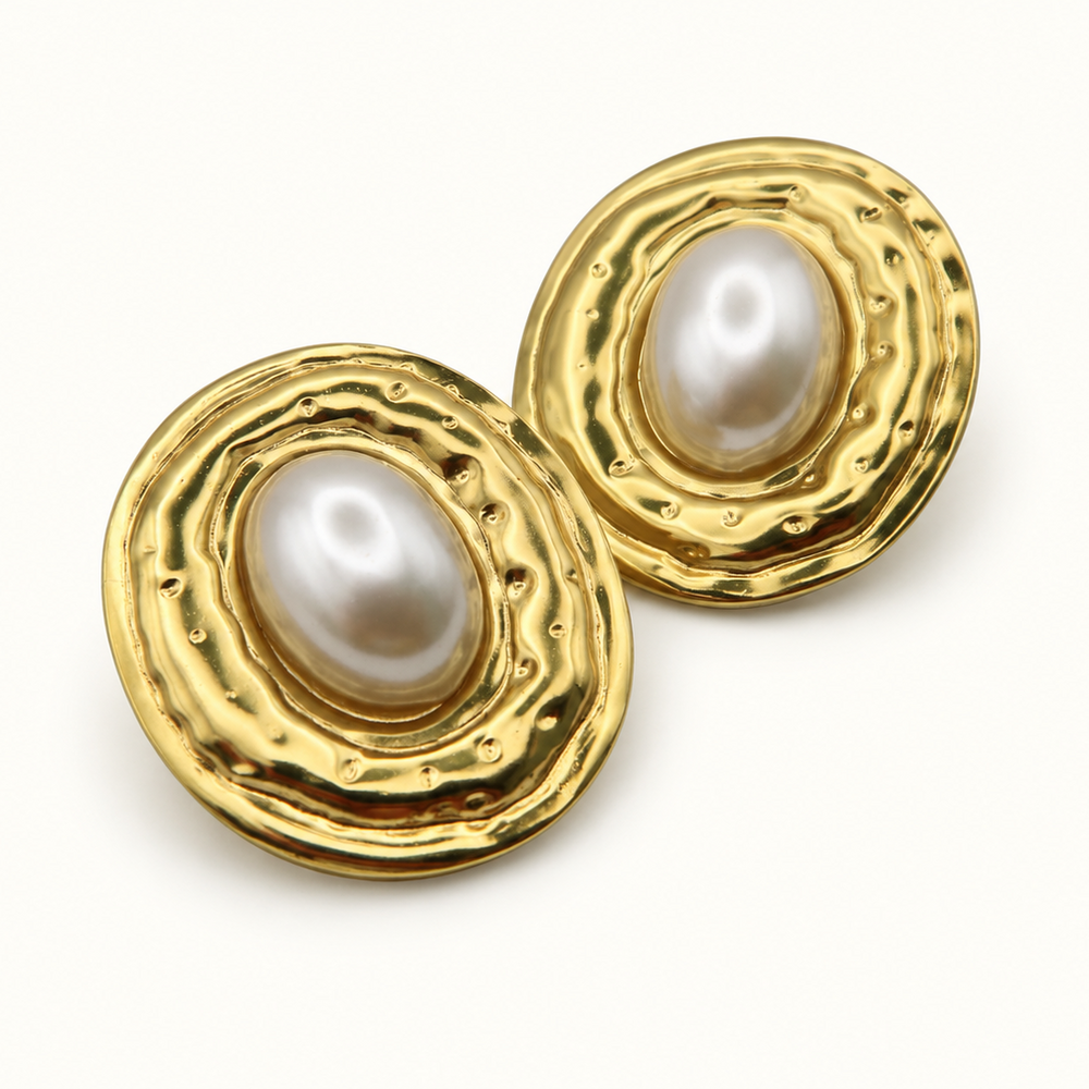 A pair of gold-toned oval earrings with textured, wavy edges and a central white freshwater pearl, shown on a clean white background.
