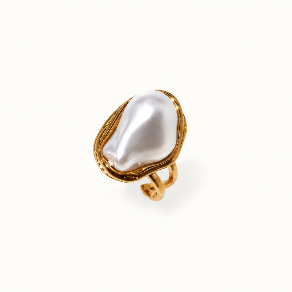 A gold ring featuring a large, irregular white baroque pearl, photographed on a clean white background.