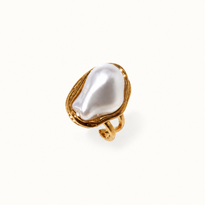 A gold ring featuring a large, irregular white baroque pearl, photographed on a clean white background.
