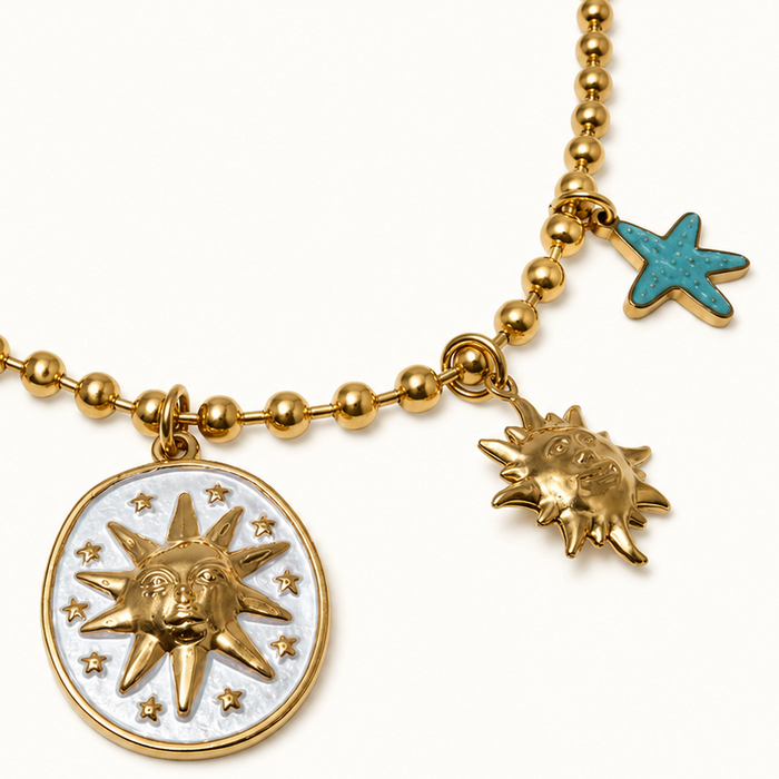 A gold-toned beaded necklace featuring a central round pendant with a sun motif on a white background, flanked by three smaller sun charms and two turquoise starfish charms on a white studio background.