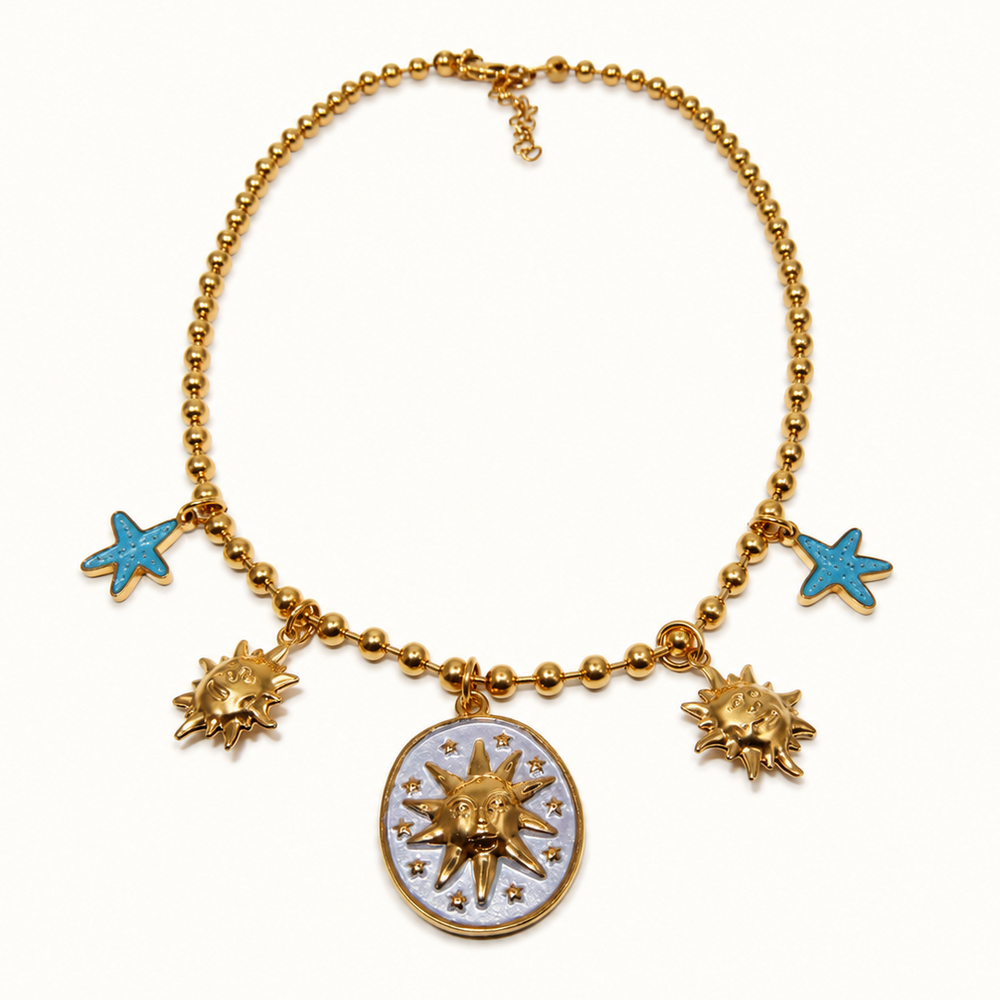Gold beaded necklace with a central oval medallion and three dangling sunburst charms, plus two small blue starfish charms, shown on a plain white background.